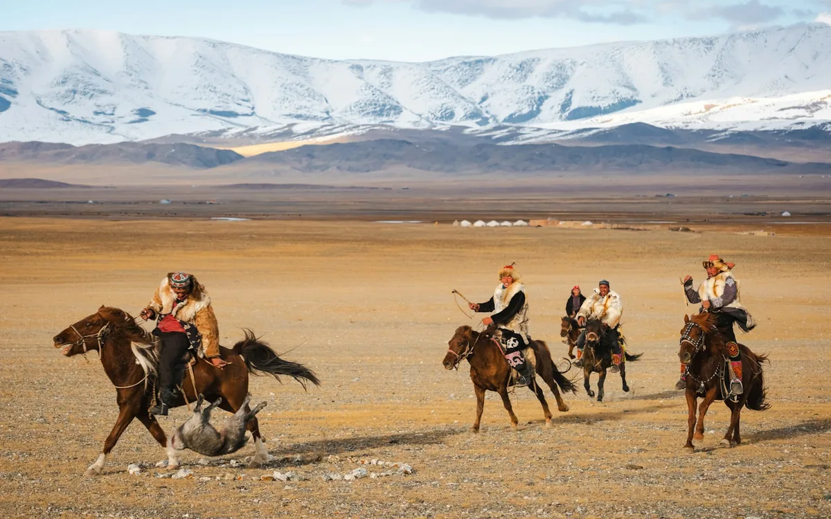 Riders on horseback crossing open grassland in Mongolia