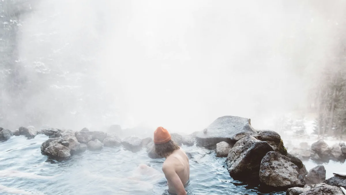 Steam rising from a natural hot spring pool surrounded by rock