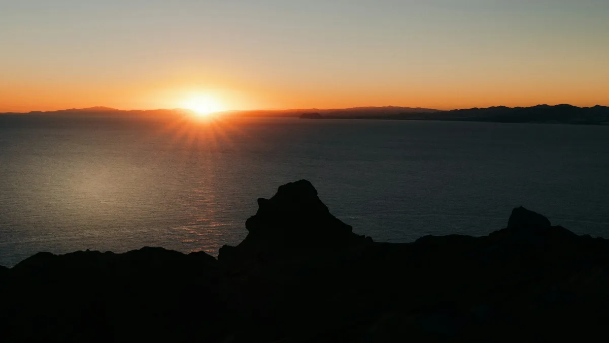 Sunrise light over mountains and coastline seen from a summit