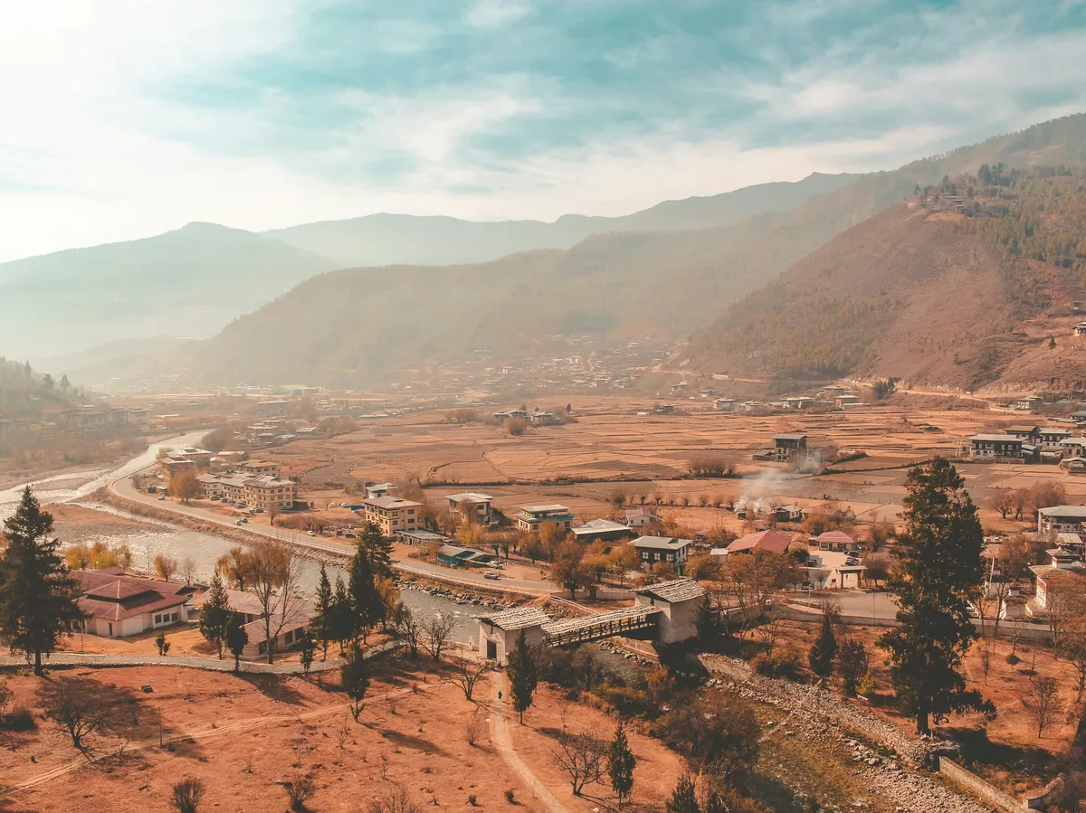 Aerial view of a Bhutanese town surrounded by forested mountains