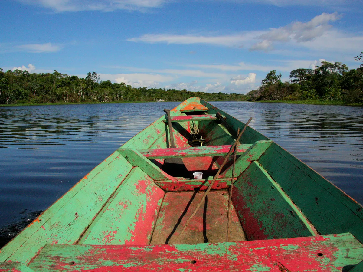 A canoe resting on a still Amazon lake in Bolivia's rainforest lowlands