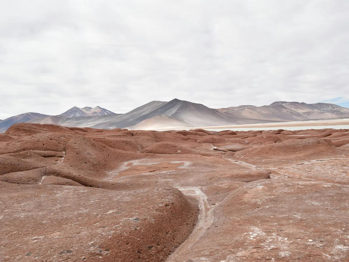 A dirt road cutting through the volcanic desert landscape near San Pedro de Atacama, Chile