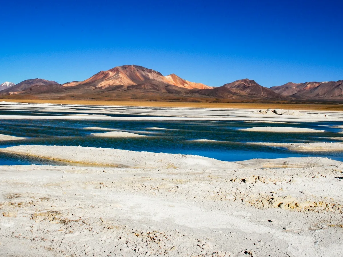 A quiet Andean lake shore with mountains rising in the background