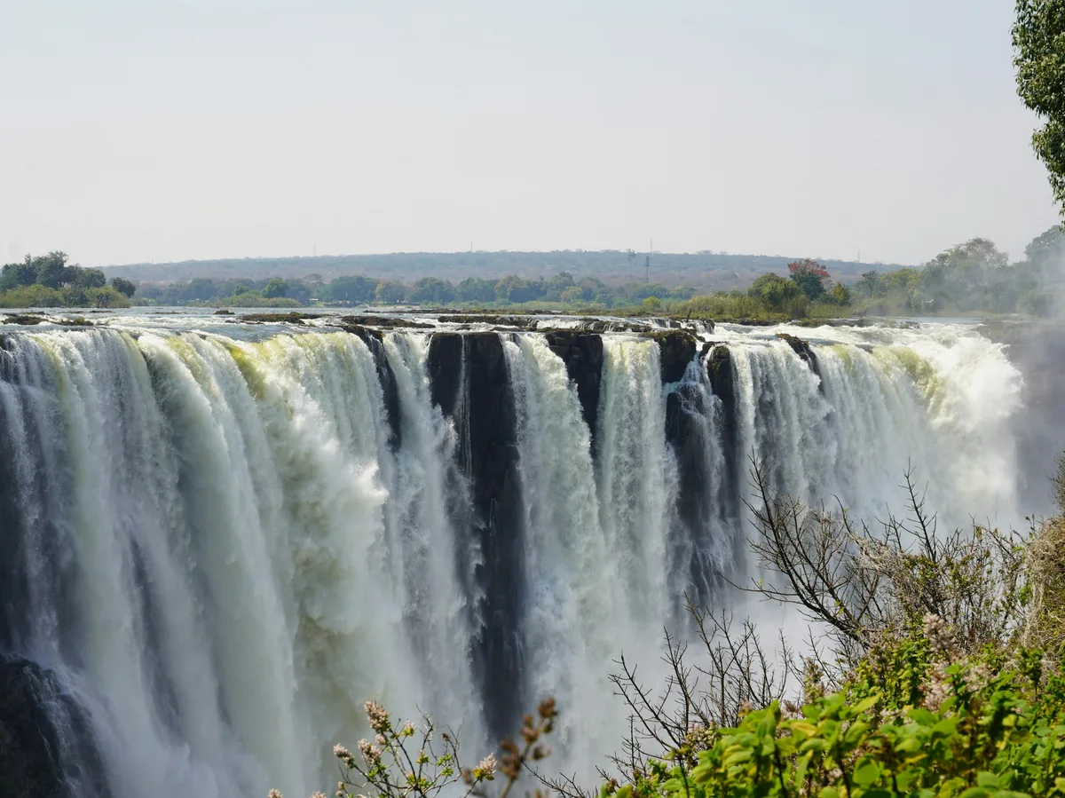 Wide view of Victoria Falls with mist rising over the Zambezi River gorge