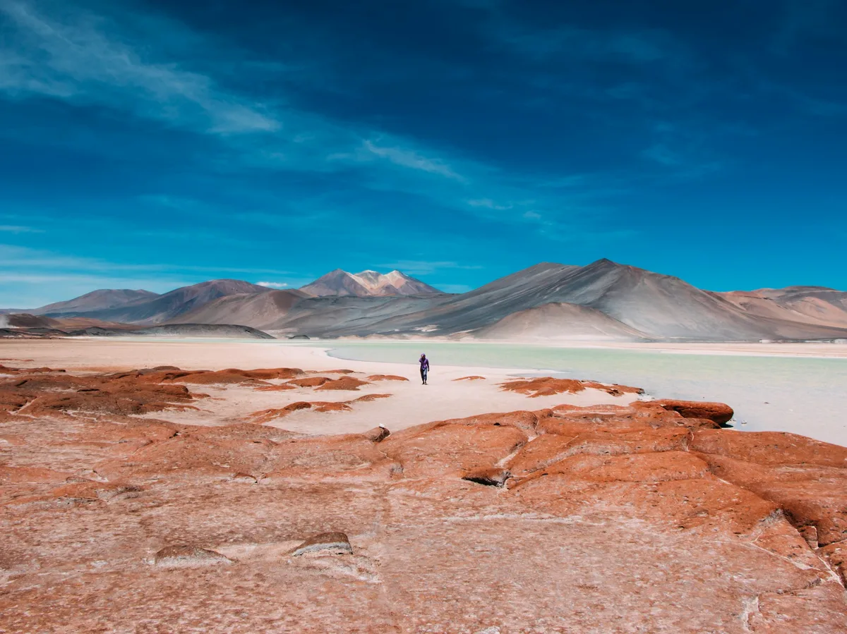 Sun-baked salt desert with a distant volcano in the Atacama Desert, Chile