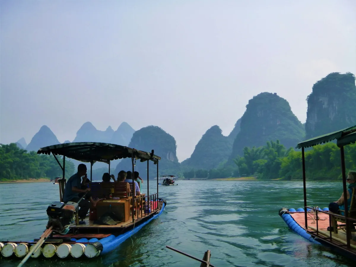 A boat carrying visitors along the Li River past limestone karst hills near Guilin