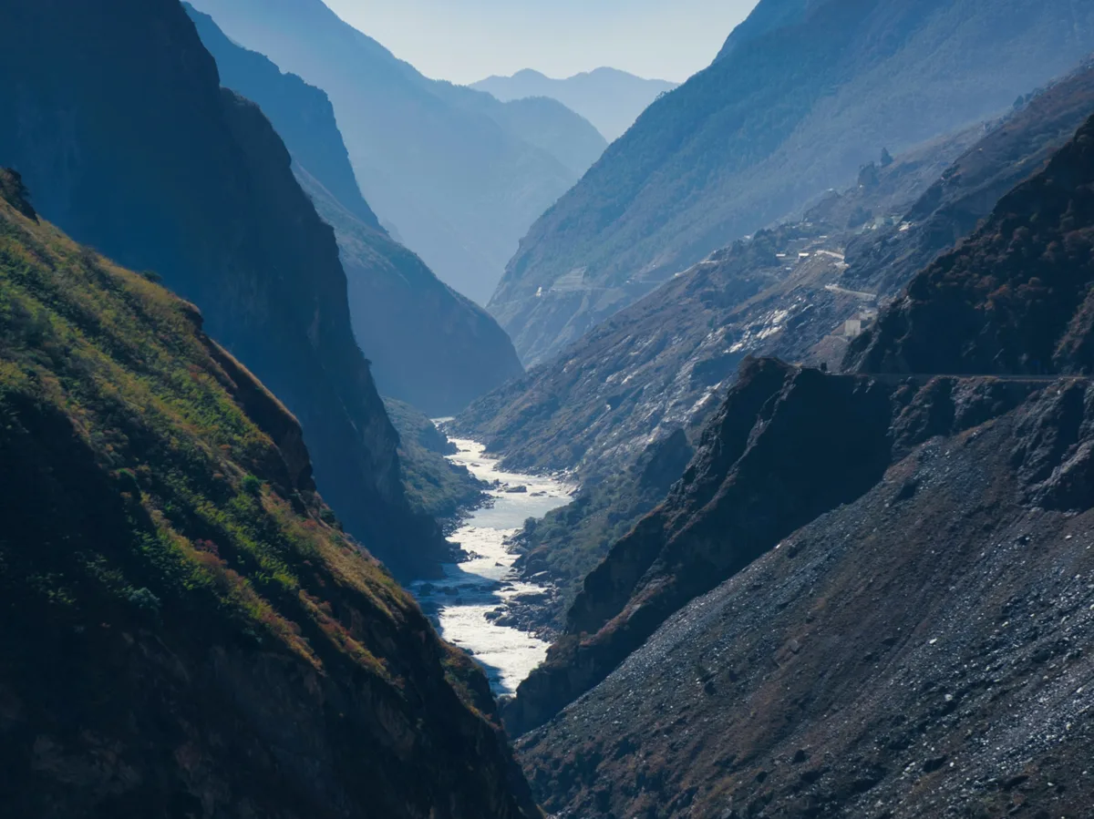 A river running through a lush green valley near Tiger Leaping Gorge, Yunnan
