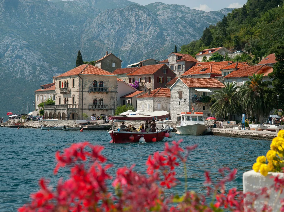 Boats moored in front of the pastel-coloured waterfront houses of Perast, Montenegro