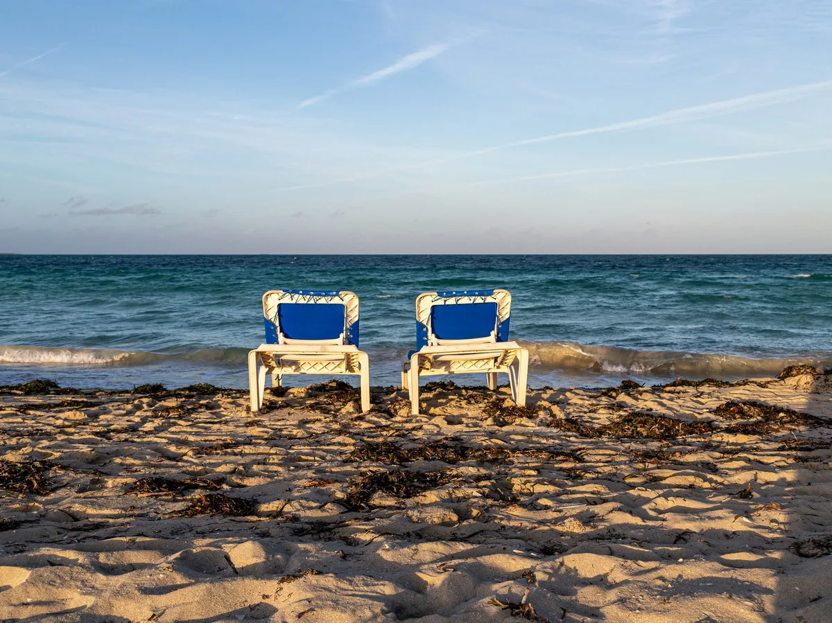 Two beach loungers facing the turquoise water on a sandy beach in Varadero, Cuba