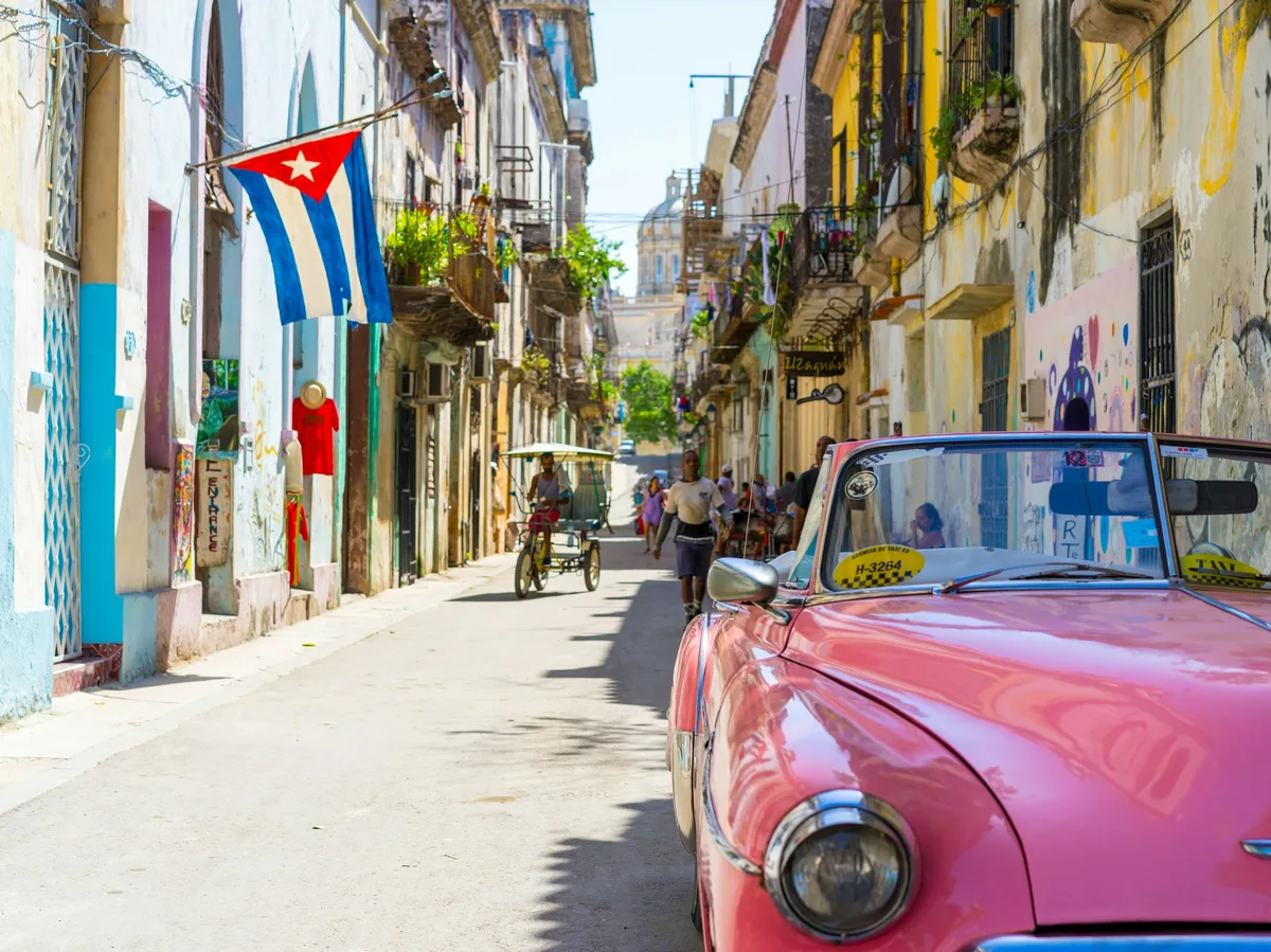 A pink vintage convertible car parked on a street in Havana, Cuba