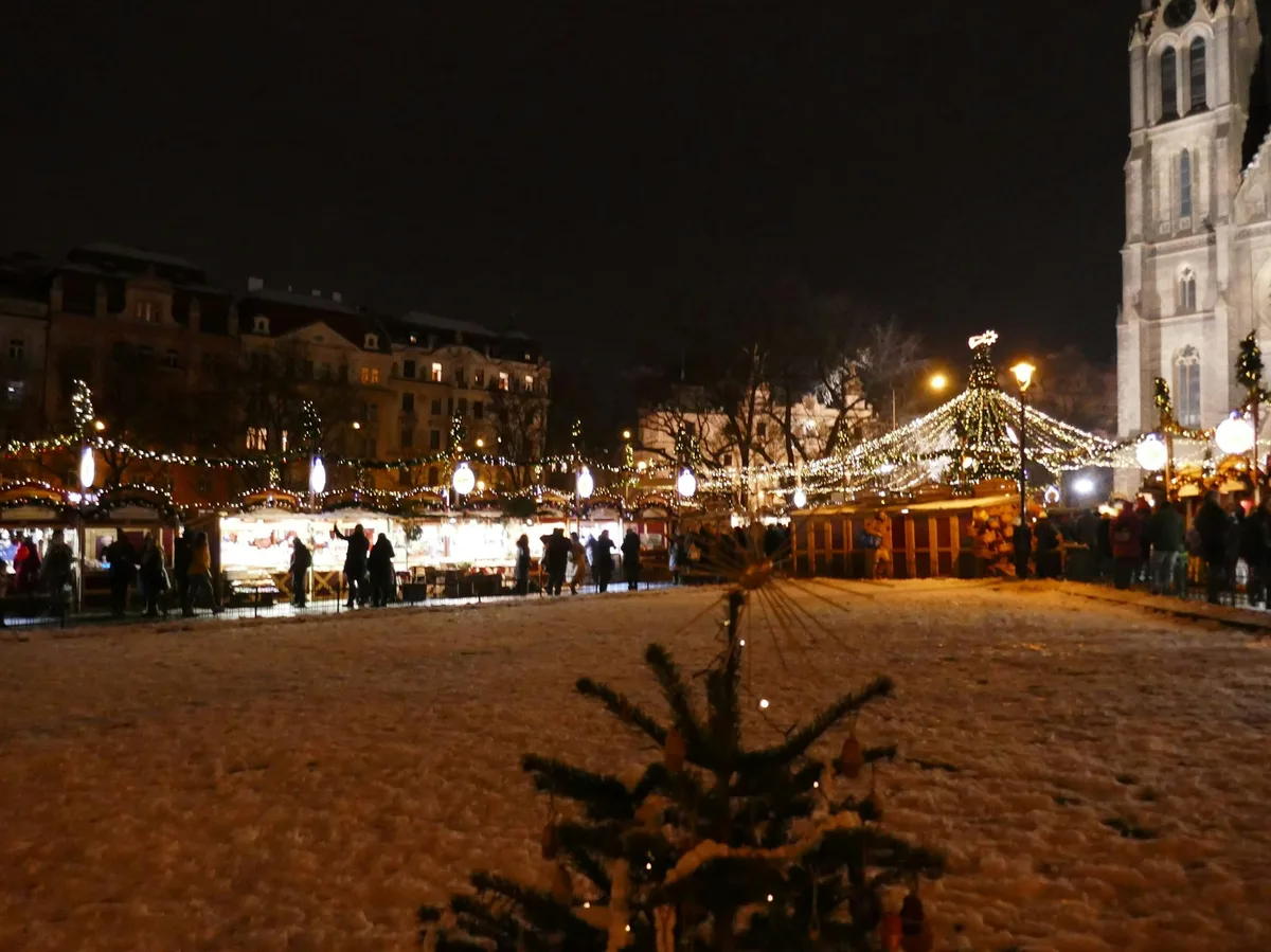 Wooden stalls and a lit Christmas tree at a traditional Central European Christmas market at night