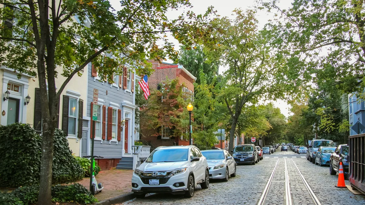 A row of historic brick townhouses on a tree-lined street