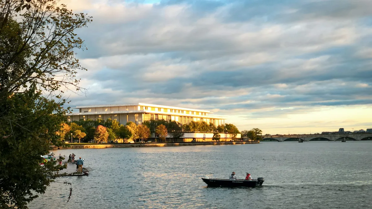 A boat cruising on a river at sunset with a city skyline behind