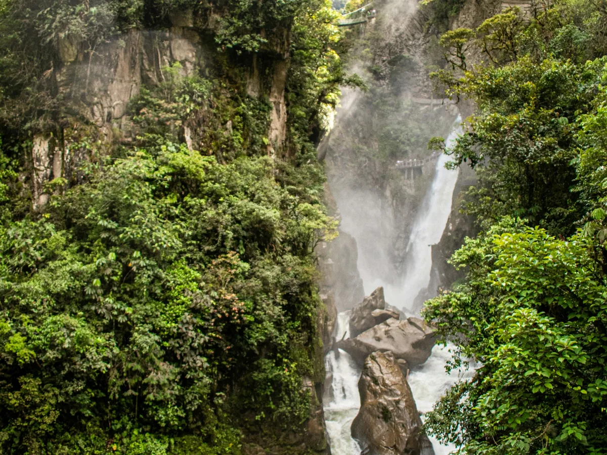 A powerful waterfall cascading through a lush green forest near Baños, Ecuador