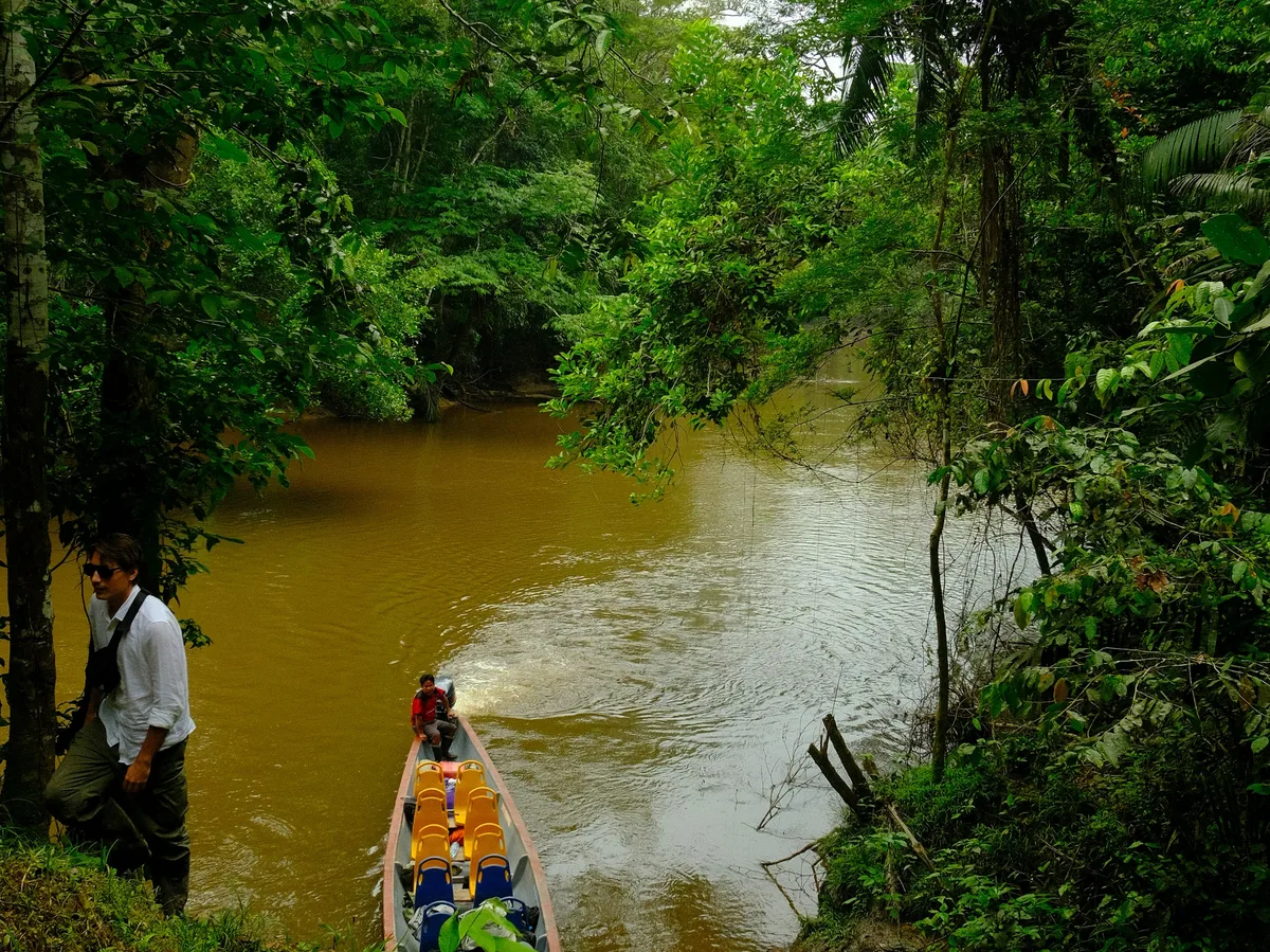 A couple paddling a canoe on a quiet Amazon tributary in Ecuador