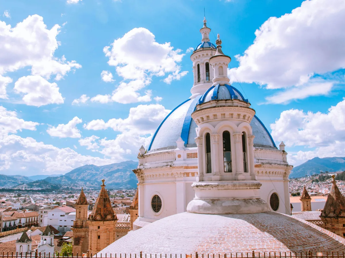 A white colonial-era church dome in Cuenca, Ecuador, under a blue sky