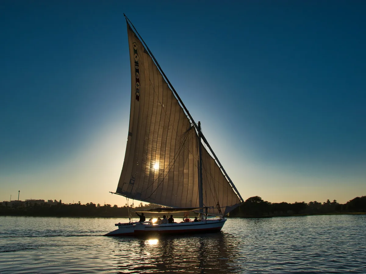 A traditional felucca sailboat on the Nile River at sunset