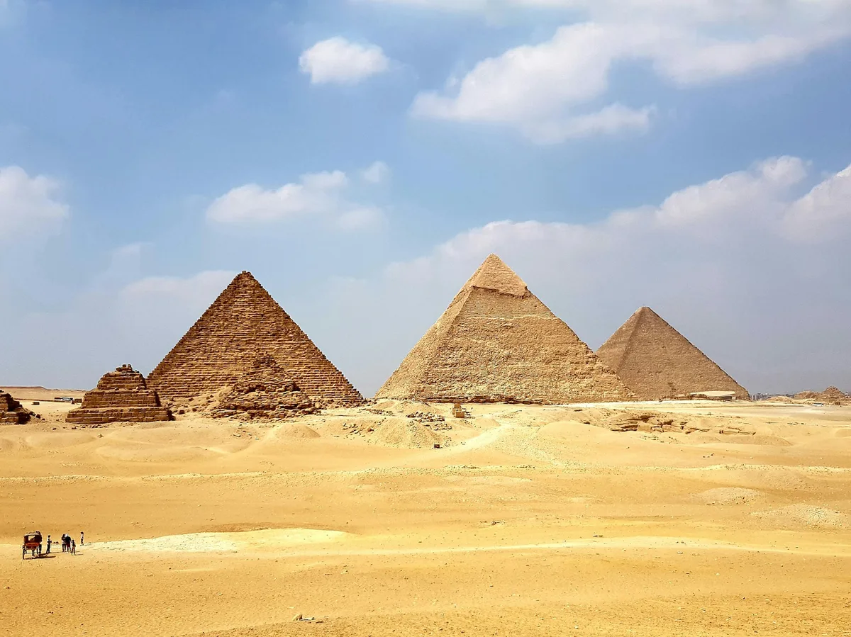 The Pyramids of Giza rising from the desert under a clear blue sky