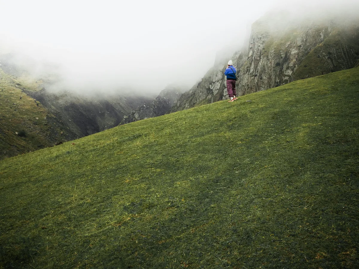 A lone hiker on a grassy mountain slope in the Georgian Caucasus