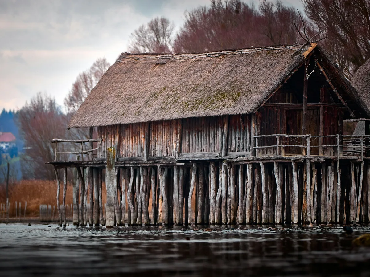 Wooden stilt houses built over a lake at dusk, in the style of West Africa's stilt villages