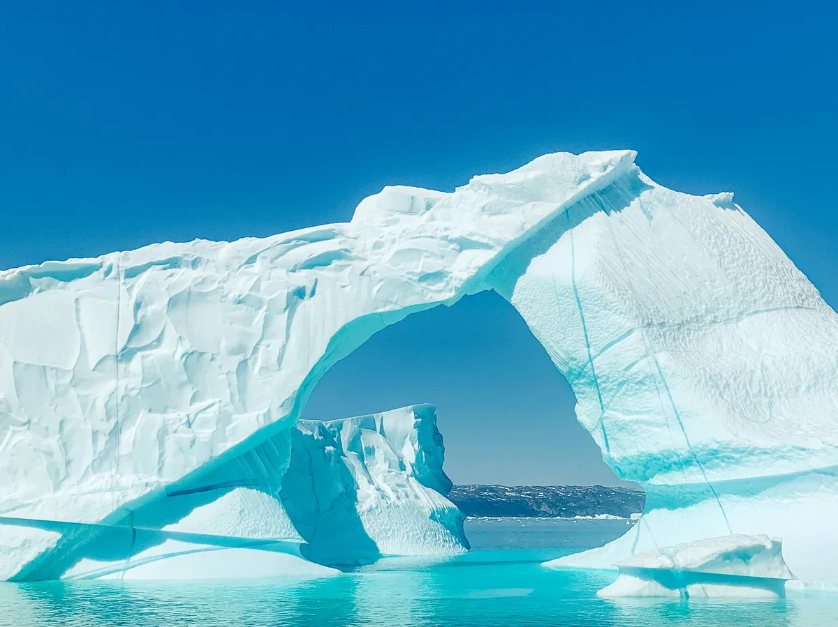 A large iceberg floating under a blue sky in Disko Bay, Greenland