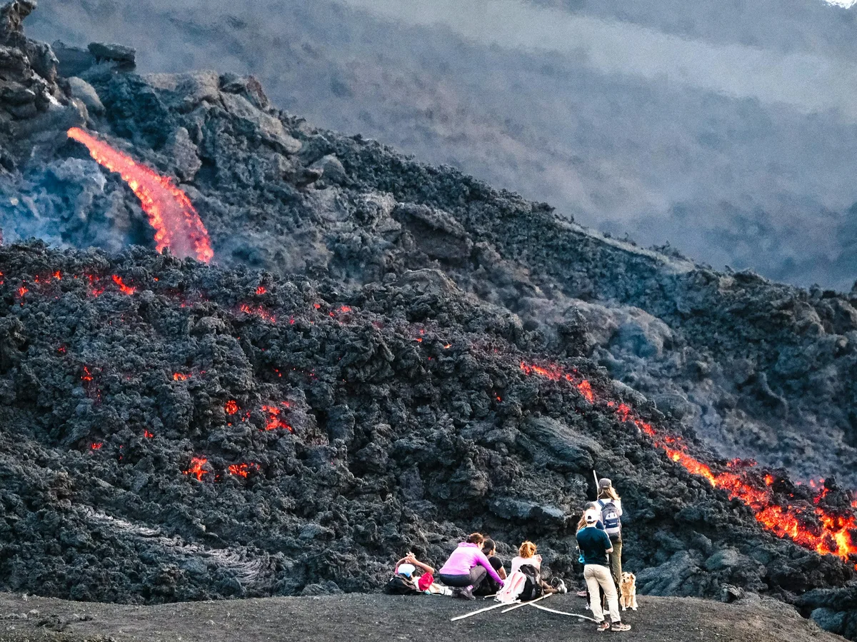 Hikers standing near glowing lava at Pacaya volcano, Guatemala, during daytime