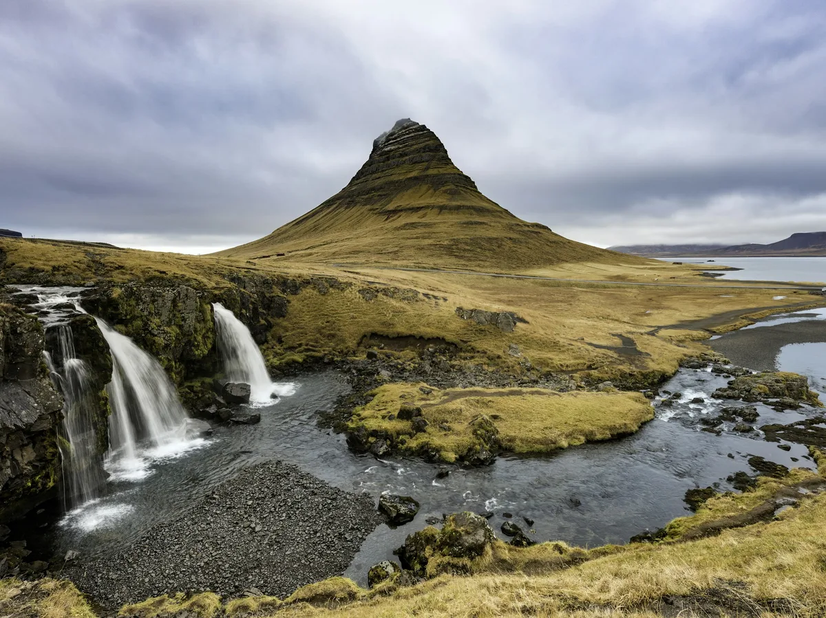 Kirkjufell Mountain reflected beside a waterfall on the Snaefellsnes Peninsula
