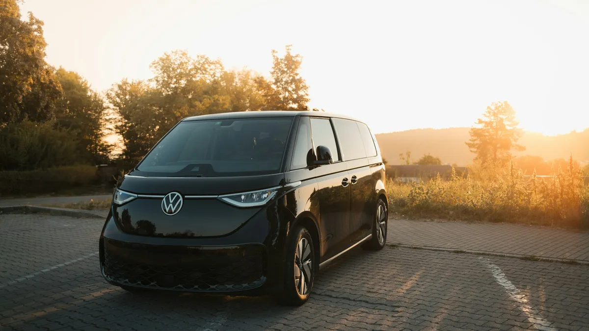 A black Volkswagen ID.Buzz electric van parked on a countryside road at sunset