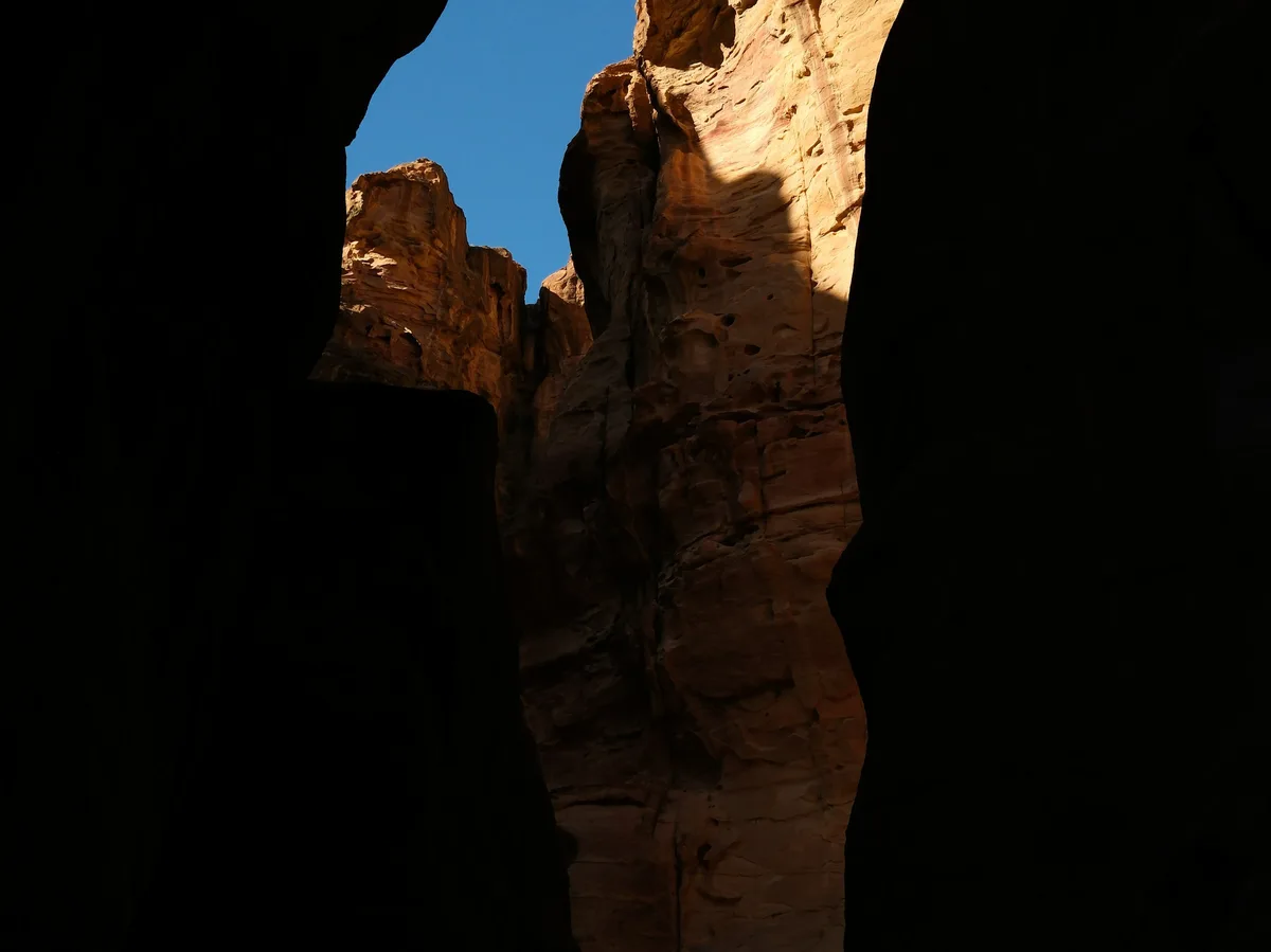 Sunlight streaming through the narrow Siq canyon leading into Petra, Jordan
