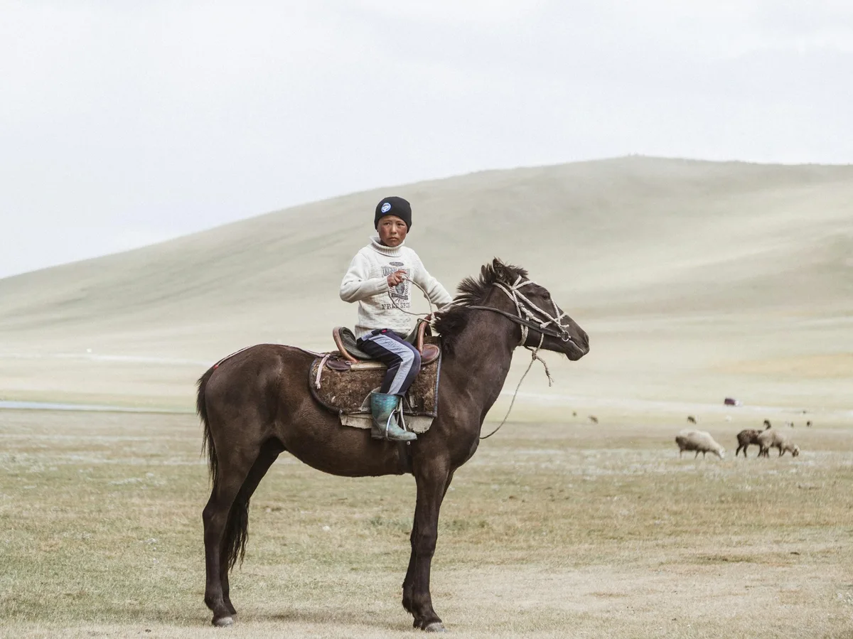 A boy riding a horse in the Kyrgyz mountains