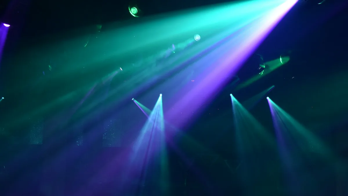 Colorful teal and purple spotlights cutting through a hazy nightclub atmosphere