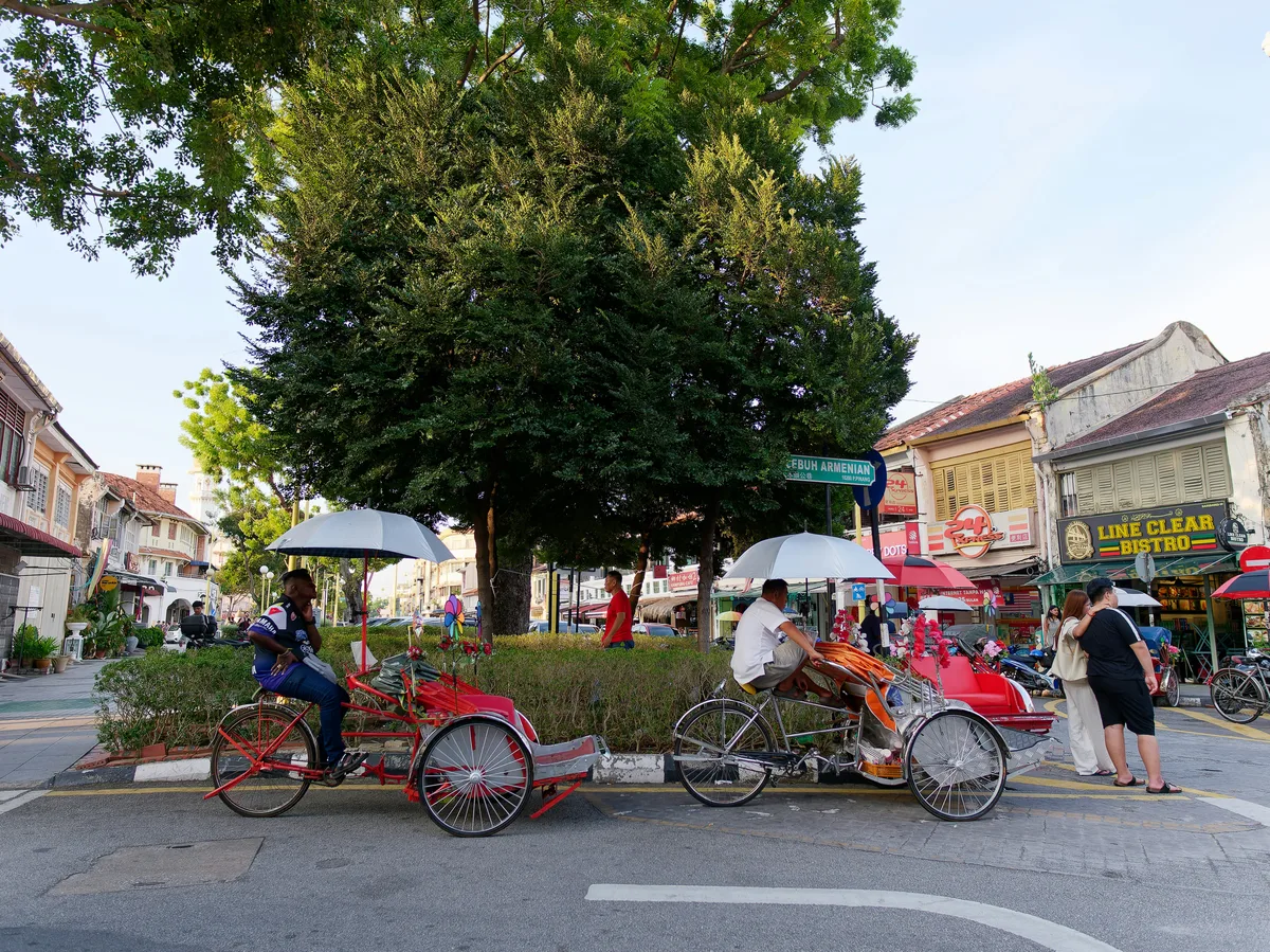 A trishaw and pedestrians on a heritage street in George Town, Penang, Malaysia