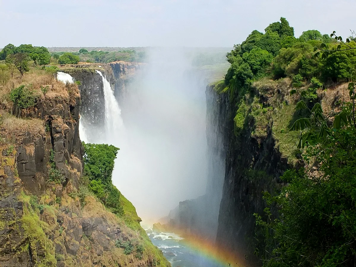 A rainbow rising from the mist of Victoria Falls, Zimbabwe