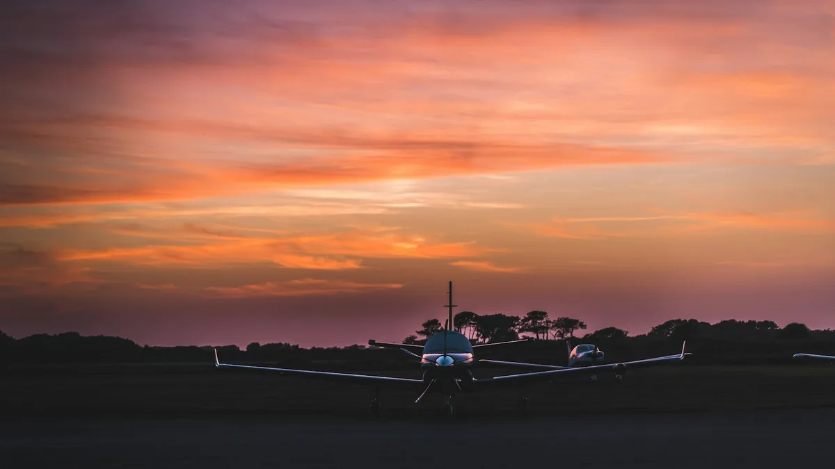 A small propeller plane on an airport runway at sunset