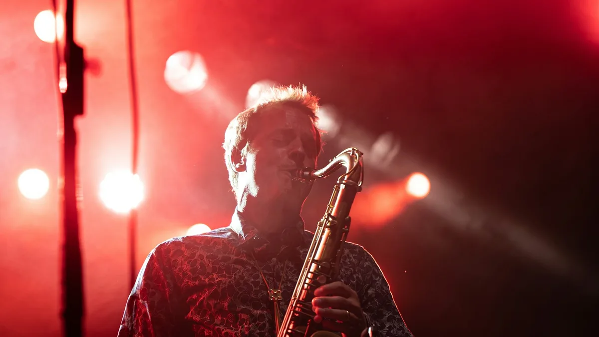 A jazz club stage lit up at night with a saxophone player