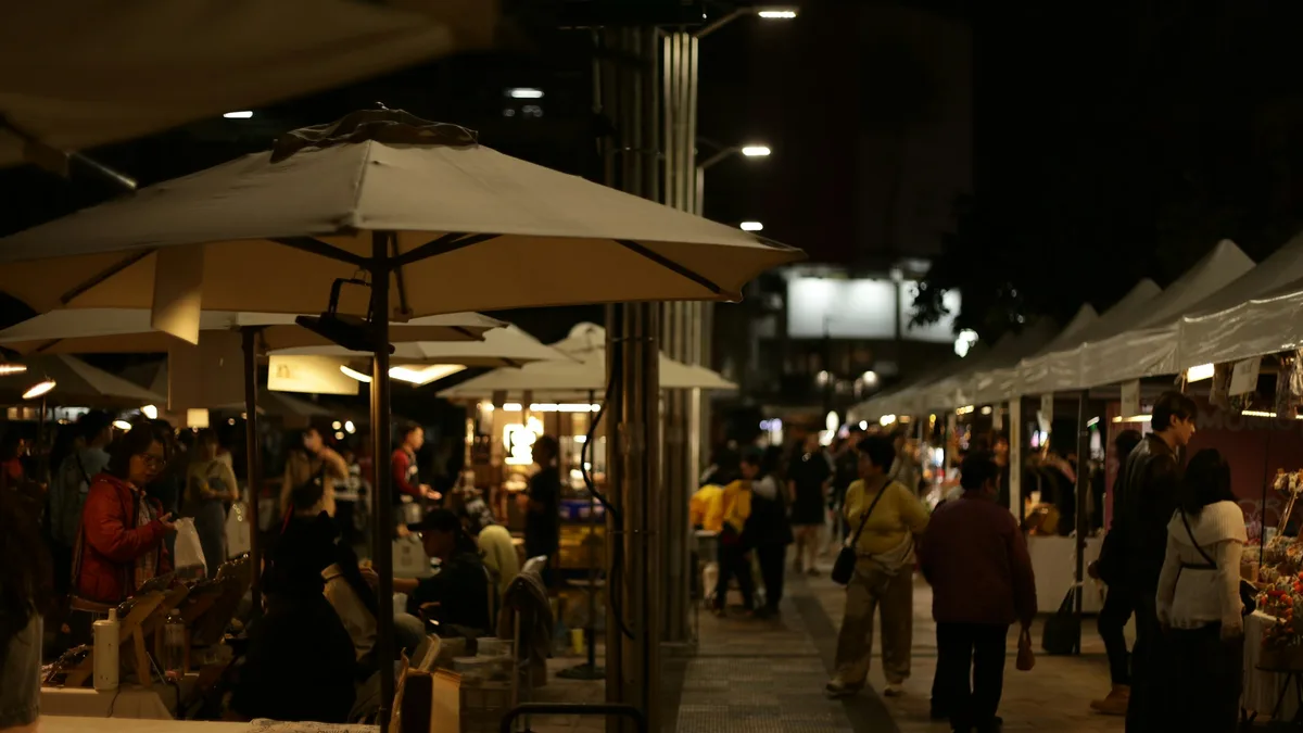 A lively outdoor market with vendor stalls and string lights