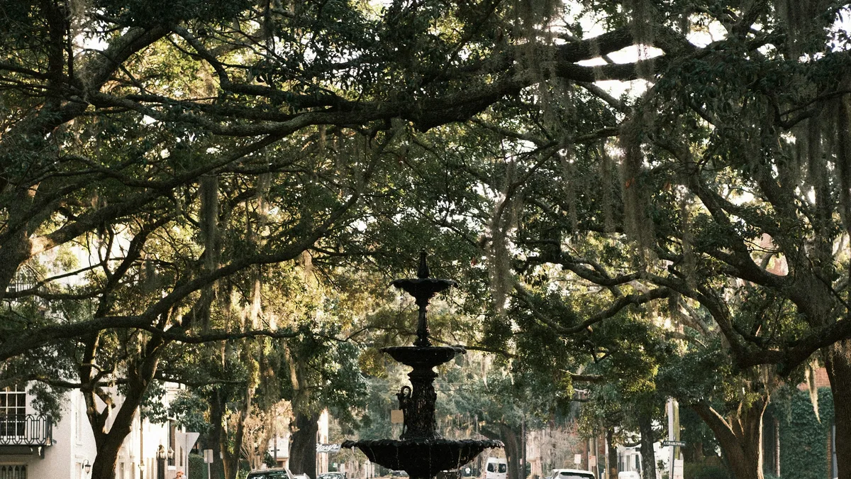 An ornate fountain under a canopy of moss-draped oak trees