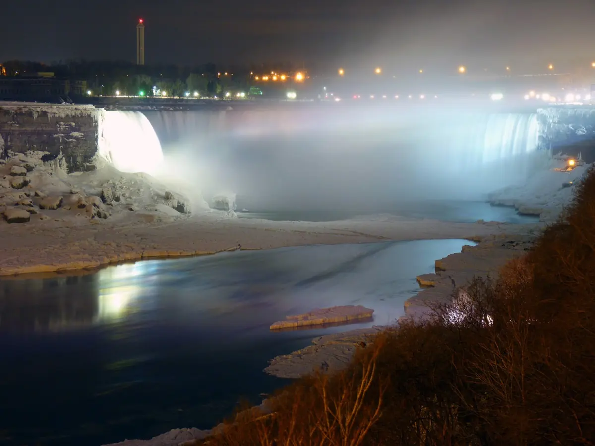 Horseshoe Falls illuminated at night with fireworks over the water