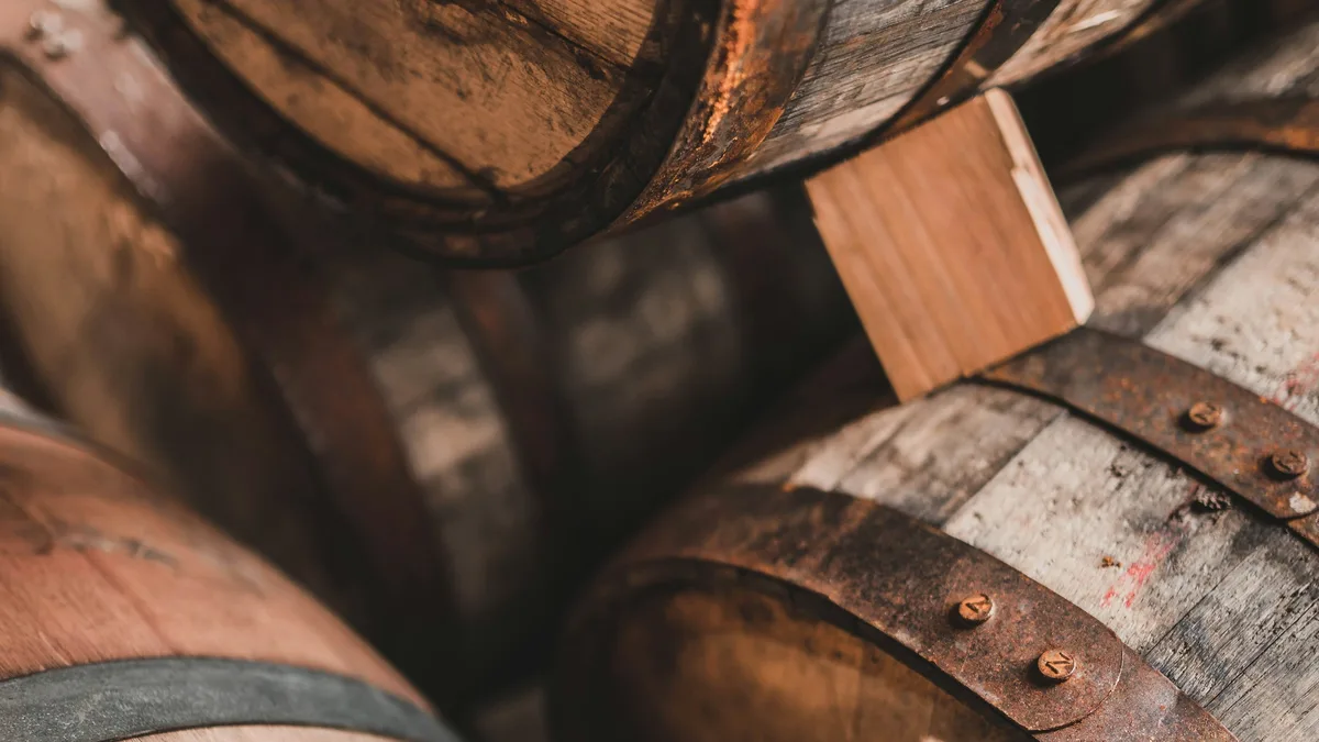 Rows of weathered oak barrels aging in a distillery cellar
