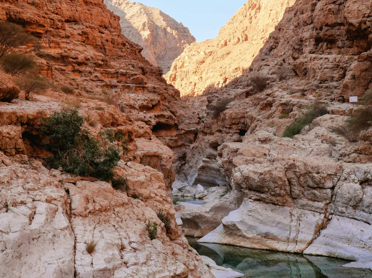 Sunlit canyon and turquoise pool at Wadi Shab, Oman