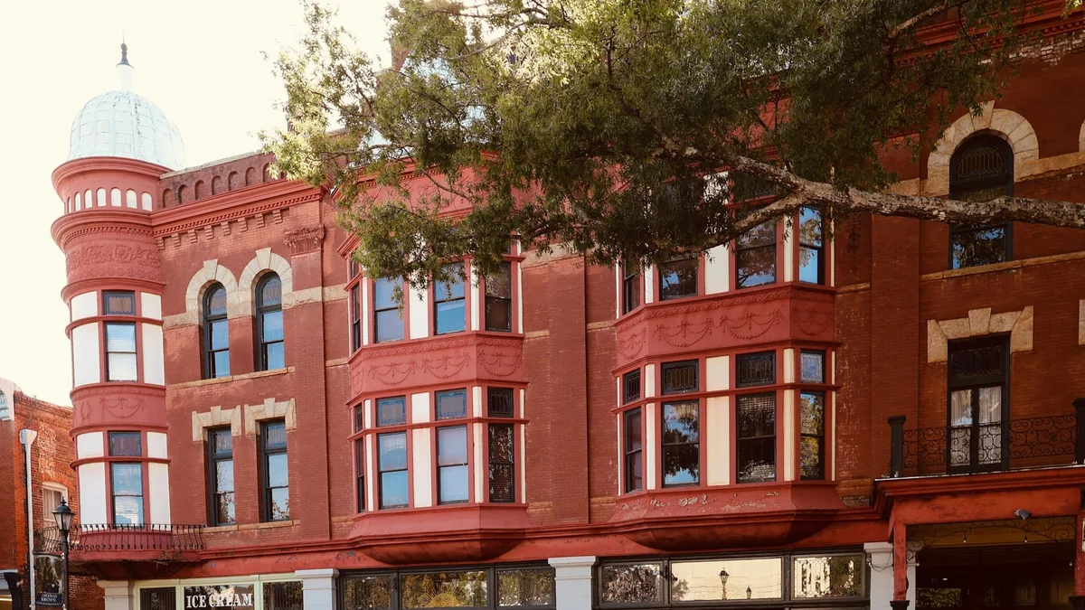 A historic red-brick corner building with bay windows and a street-level storefront