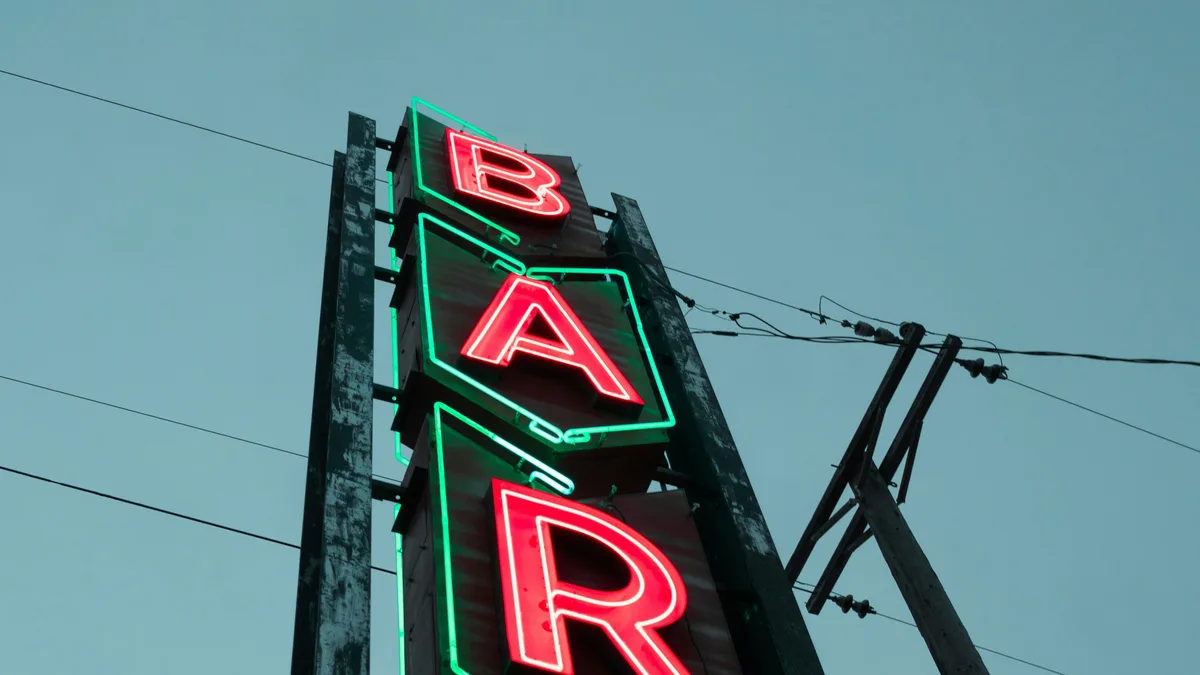 A vintage neon bar sign glowing at dusk