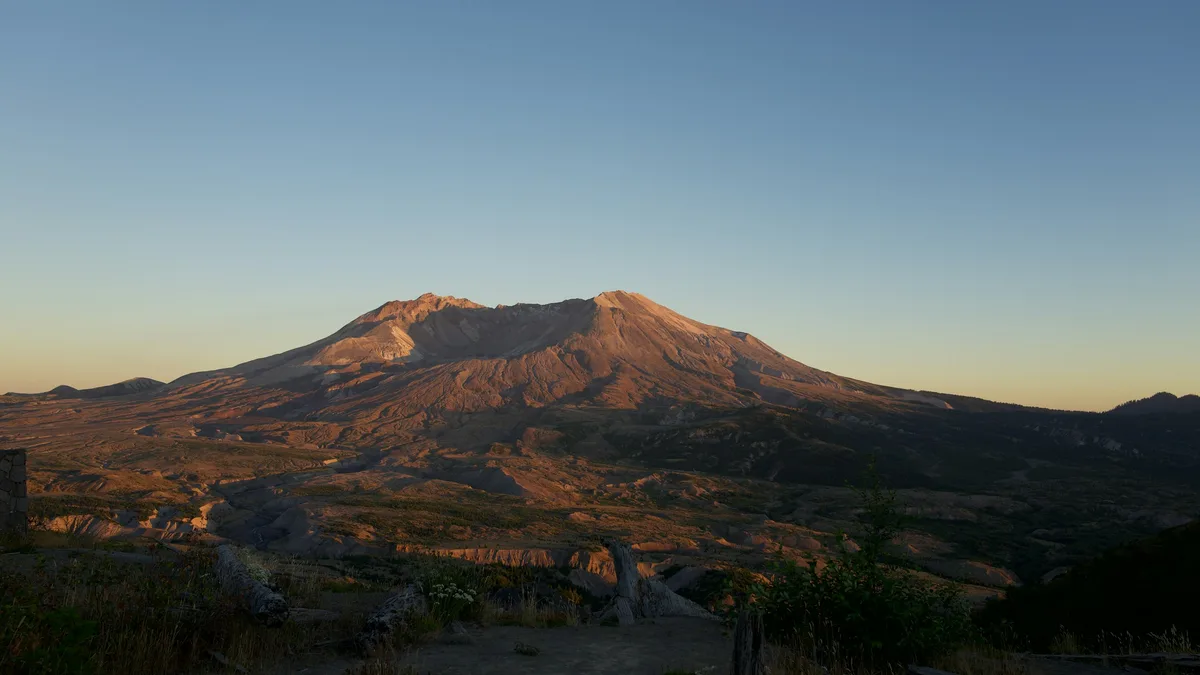 A volcanic mountain with a visible crater and surrounding devastated forest