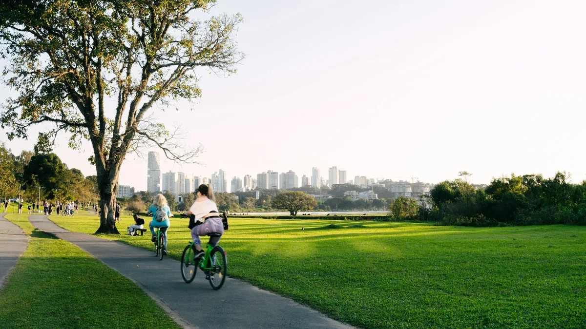 Cyclists riding e-bikes through a green city park