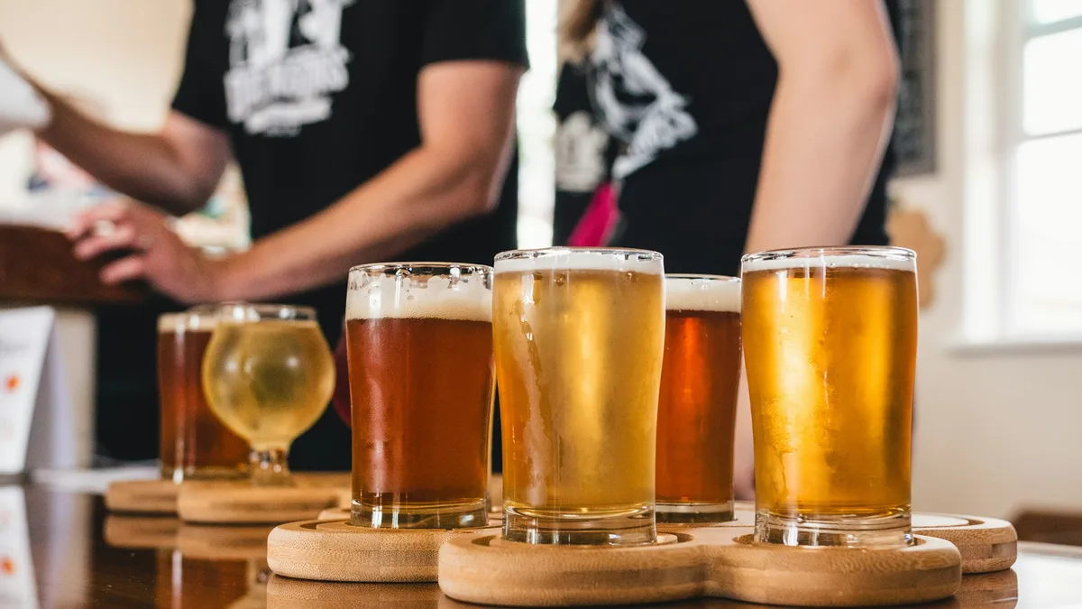 Glasses of cider and craft beer lined up on a wooden tasting table